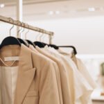 Women's clothes in beige colors on open hangers in store. Selective focus, copy space.